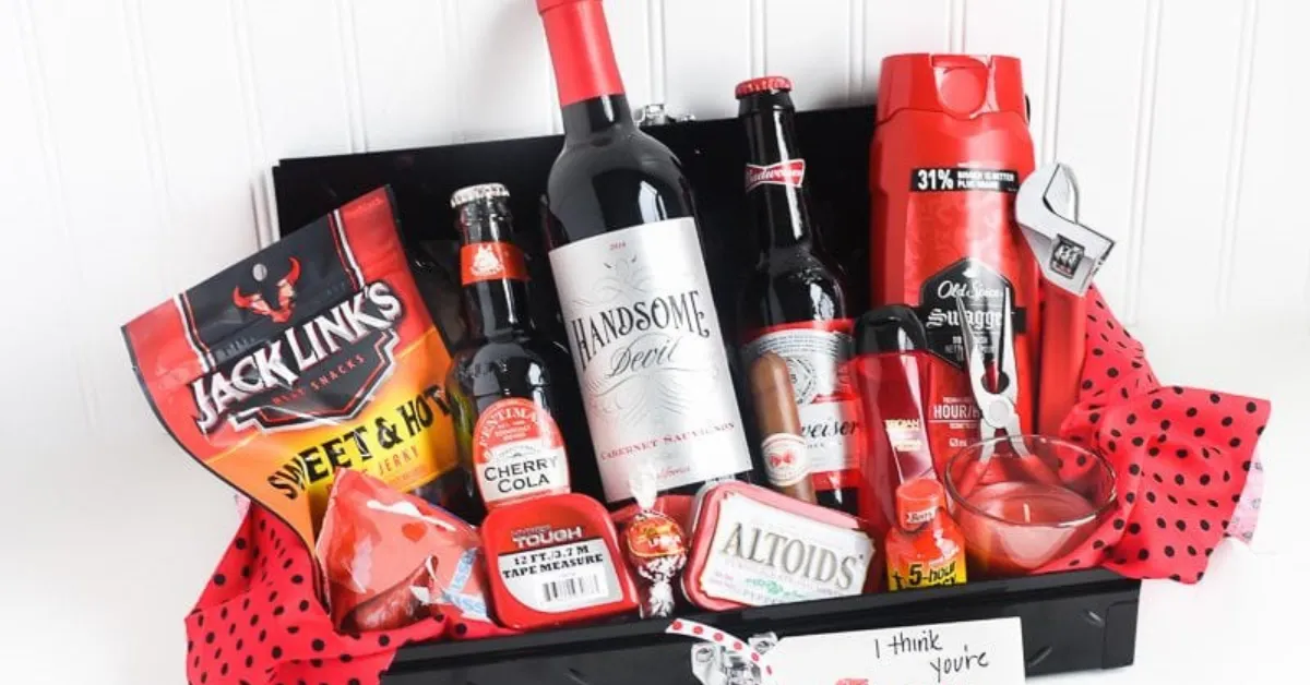 Valentine-themed gift basket for men with wine, beer, Jack Link’s beef jerky, grooming products, candy, and small accessories arranged in a black tray with red decorations.