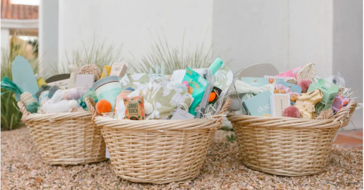 Three woven Easter baskets filled with pastel-colored gifts, treats, and small items, arranged outdoors on a gravel surface.