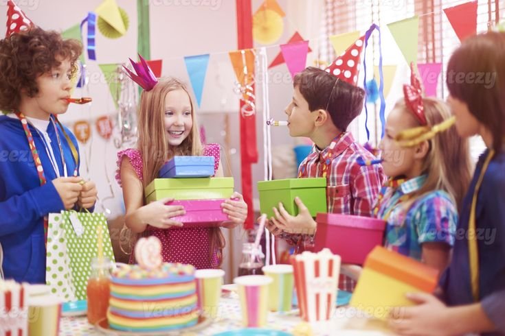 Colorful birthday party with decorated cake, balloons, gifts, and guests celebrating together.