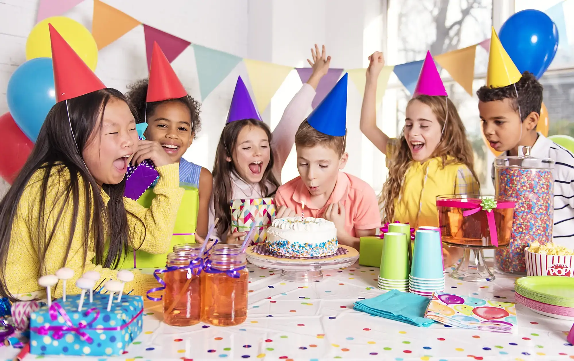 Colorful kids birthday party with balloons, birthday cake, decorations, and children enjoying activities